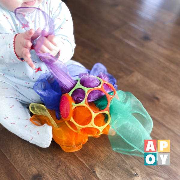 baby pulling sensory scarf out of ball