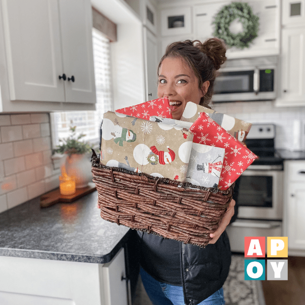 woman holding basket of books wrapped in christmas wrapping paper